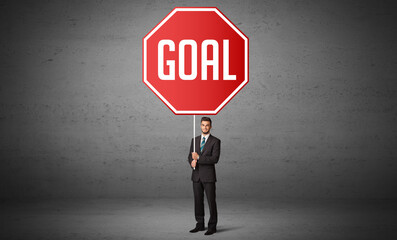 Young business person holding road sign with GOAL inscription, new rules concept