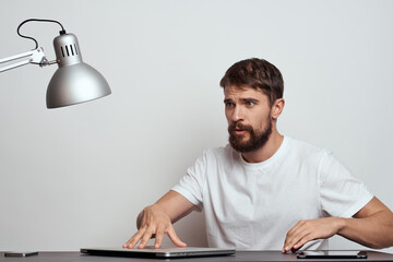 A man sits at the work table of a technology manager communication lamp