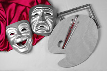 Comedy And Tragedy Masks With Purple Drapery, Art Palette And Brushes On A Light Background. Theater Symbol.