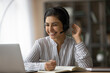 © fizkes - Overjoyed millennial Indian female student in headphones look at laptop screen study online from home. Happy young mixed race woman in earphones talk on video call with teacher. Virtual event concept.