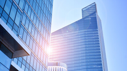 Downtown corporate business district architecture. Glass reflective office buildings against blue sky and sun light. Economy, finances, business activity concept. Rising sun on the horizon.