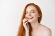 Beauty and skincare. Close-up of happy redhead woman with pale perfect skin, laughing and showing white teeth, standing naked on studio background