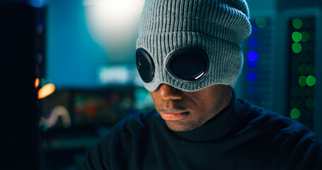 Black hacker in mask using computer