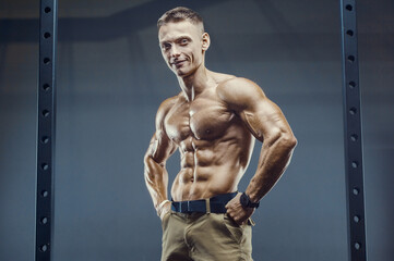 Fitness man pumping up abs muscles in gym