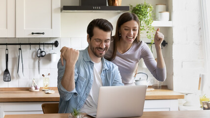 Wide banner panoramic view of overjoyed man and woman celebrate online lottery win on laptop. Excited young Caucasian couple feel euphoric triumph with good news or amazing sale deal on computer.