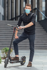 Wall Mural - Young man riding electric scooter in medical mask in face