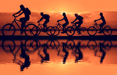 Sporty company friends on bicycles outdoors against sunset. Silhouette five 5 cyclist going along coast. sunlight. Sport team. Group of people.  Empty Copy Space for inscription.