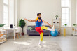 © Studio Romantic - Clumsy, funny man in headband and colorful blue, red and yellow retro sportswear doing front leg raise toe tap gymnastic exercise in living-room. Concept of weight loss and fitness workout at home