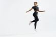 © Liubov Levytska - Fit and healthy sports woman runner jumping and looking behind. Female athlete in workout clothing doing exercises on white background, staring at empty space