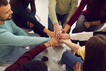 Wall Mural - From above view of diverse senior and young people sitting in circle and putting hands together in community meeting or group therapy session. Concept of support, unity, success, help and trust