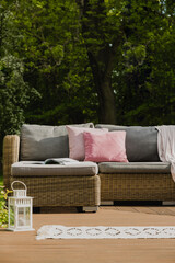 Wall Mural - Pastel pink pillows on grey sofa in green garden with wooden terrace