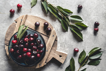 Sticker - top view of red cherries on a bowl with slices of peaches on a wooden kitchen board with knife on a white background