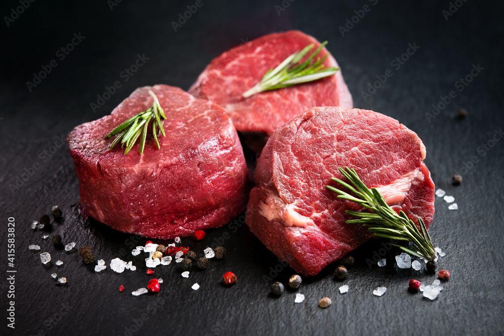 Raw beef filet mignon steaks with rosemary, pepper and salt on dark rustic board - obrazy, fototapety, plakaty 