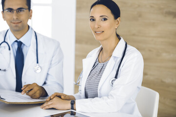 Two doctors discussing treatment problems while sitting at the desk in hospital office. Data in medicine and health care concept