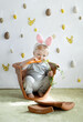 Cute young toddler boy wearing a bunny rabbit costume chewing on a carrot sitting in a flower pot. Happy Easter time