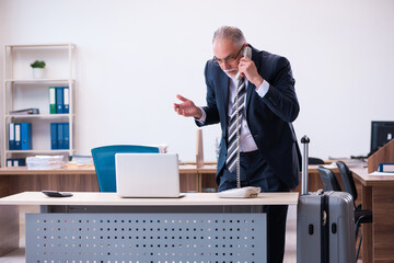 Old male employee preparing for travel in the office