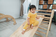 © Odua Images - baby sits alone on the slide while playing in the pikler triangle toy in the living room
