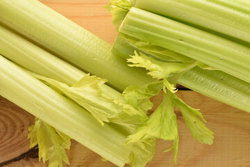 Two light green natural, juicy stalks of celery on a wooden table, close-up, top view.