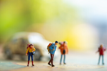 Miniature traveler standing behind a bus on a vintage map. Green nature background.