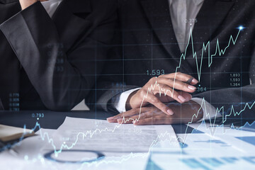 Two traders researching historic data to predict stock market behavior. Women in trading business concept. Forex and financial hologram chart over the table with the document.