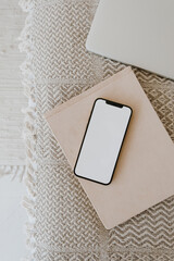 Wall Mural - Flat lay of cellphone on blanket plaid with notebooks. Blank copy space mockup template screen display. Flatlay, top view social media, web, blog, app concept.