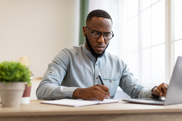 Wall Mural - Black Businessman Taking Notes Sitting Working At Workplace In Office