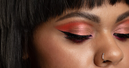 Close up of cheerful young woman with colourful makeup. Beauty portrait of black female model with vivid makeup laughing