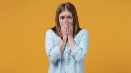 Wall Mural - Shocked worried scared blonde young woman 20s years old in casual blue shirt posing isolated on yellow background studio. People sincere emotions lifestyle concept. Covering face with hands hiding