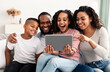 © Prostock-studio - Happy african american family holding and using digital tablet computer