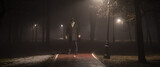 Fototapeta Londyn - strange man on the road in the forest at night in the fog