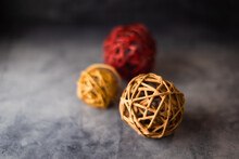 Three Colored Wicker Balls Placed Front To Back On A Concrete Surface With Pinned Focus