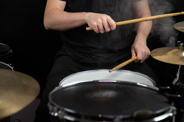 Professional drum set closeup. Man drummer with drumsticks playing drums and cymbals, on the live music rock concert or in recording studio   