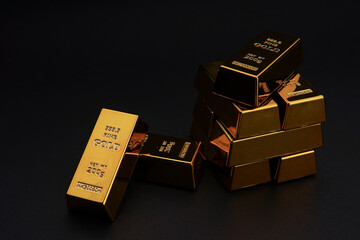 A pile of gold bar a black background. Shiny precious metals for investments or reserves.