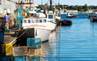 Lobster fishing boats docked in a canal with lobster traps pilled on the dock in Portland Maine