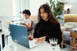 © teksomolika - Portrait of female student using net-book while sitting in cafe