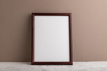 Brown wooden frame mockup on beige paper background. Blank, vertical orientation, still life.