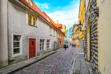 Tourists walk down a picturesque cobblestone street in a residential and business area of the medieval old town in Tallinn, Estonia