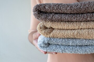 Folded clean terry towels stack on woman hand, after cleanliness laundry.