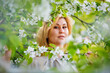 © Elena  - Portrait of a fat plump young woman with red hair and a blooming apple tree on a white floral background in a park on a spring day. Happy plus-size girl.