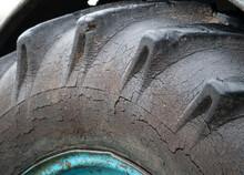 An Old Tractor Tire On Dented Rim With Cracked, Worn Rubber Tread And Sidewall. Unacceptable And Dangerous Operation Of Agricultural Machinery