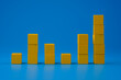 Ups and downs chart graph made with yellow wooden blocks on blue background. Trends and performance analysis concept