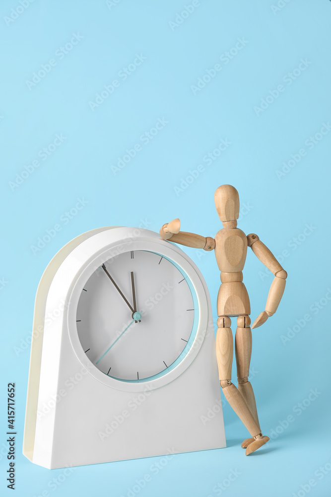 Wooden mannequin with clock on color background