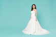 © ViDi Studio - Full length of charming pretty bride young woman 20s in beautiful white wedding dress looking camera isolated on blue turquoise color background studio portrait. Ceremony celebration party concept.