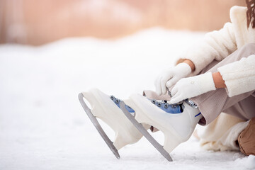 Banner woman tying shoelaces on ice skates before skating on rink