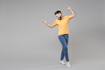 Wall Mural - Full length of young bearded attractive smiling man 20s in casual yellow basic t-shirt with outstretched hand leaning over looking aside winner gesture isolated on grey background studio portrait.