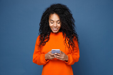 smiling beautiful young african american woman wearing casual basic bright orange sweatshirt standin