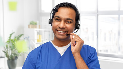 medicine, profession and healthcare concept - happy smiling indian doctor or male nurse with headset over medical office at hospital background