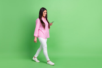 Poster - Full length body size view of attractive focused cheerful girl going using device chatting isolated over green pastel color background