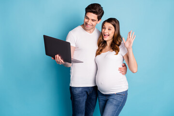 Poster - Photo of optimistic pregnant couple talk laptop wear white t-shirts isolated on cyan color background