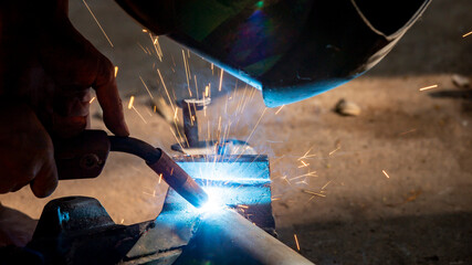 Wall Mural - Welding of steel, sparking, not wearing gloves, light colored like fireworks.